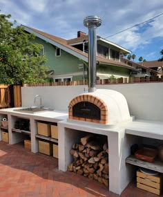 an outdoor pizza oven built into the side of a house with lots of wood stacked in it