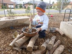 a young boy sitting on top of a pile of logs next to a bowl filled with something