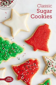 christmas sugar cookies decorated with icing and sprinkles on a white surface