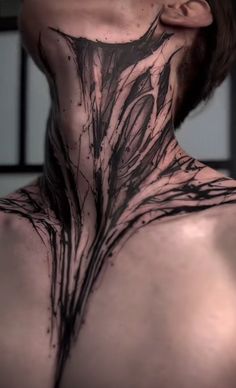 the back of a man's neck is covered in black ink and has an intricate design on it