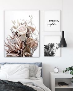 three framed pictures hang on the wall above a bed in a white room with a black and white dog