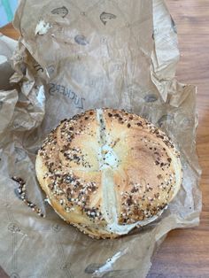 a bagel sitting on top of a piece of wax paper covered in sesame seeds