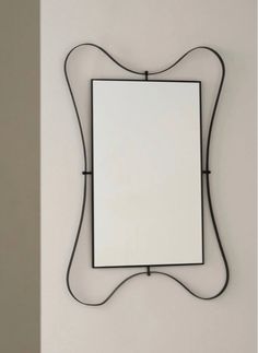 a mirror mounted to the side of a wall next to a white wall with a black metal frame