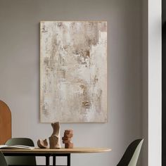 an abstract painting hangs on the wall above a dining room table with chairs around it