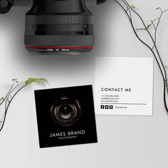 a camera and business card sitting on top of a white table next to some plants