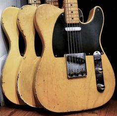 two guitars are stacked on top of each other in front of a wall and floor