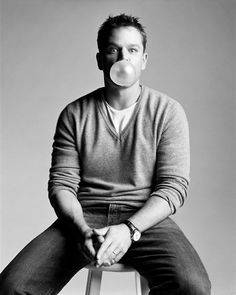 a man sitting on top of a stool with a pacifier in his mouth while wearing a sweater