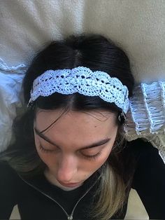 a woman laying on top of a bed wearing a headband with crochet