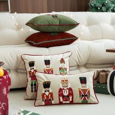 christmas pillows and gifts on the floor in front of a white couch with holiday decorations