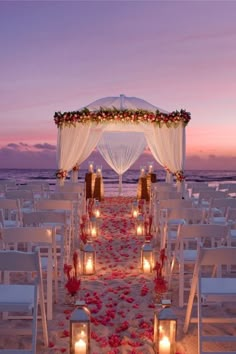 a wedding setup with candles and flowers on the beach