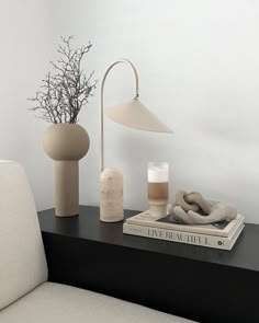 a black table topped with two vases and a lamp next to each other on top of a white couch