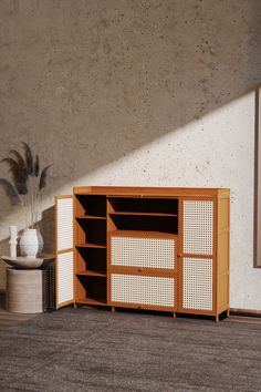 a wooden cabinet sitting on top of a carpeted floor next to a white vase