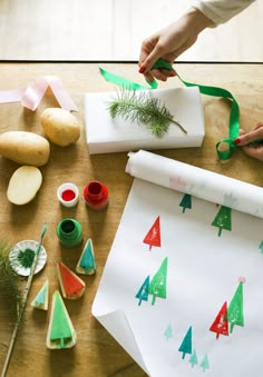 someone is making christmas trees out of wrapping paper and other crafting supplies on a table