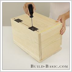 a person is using a drill to attach the top of a wooden box with nails