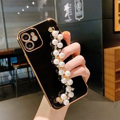 a woman's hand holding an iphone case with pearls on it