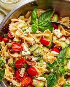 a bowl filled with pasta, cucumber and tomato salad on top of a table