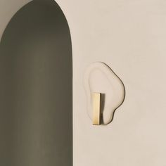 a white wall with a gold handle on it and a round shaped object in the corner