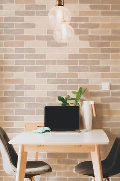 a laptop computer sitting on top of a wooden table in front of a brick wall