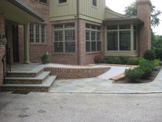 a brick house with steps leading up to the front door and landscaping area on either side