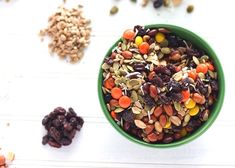 a green bowl filled with nuts and raisins on top of a white table