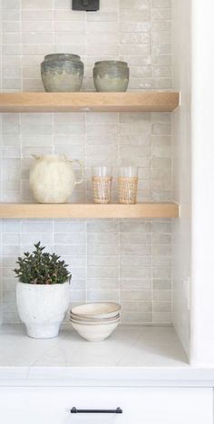 the shelves in this kitchen are filled with dishes and cups, including one planter