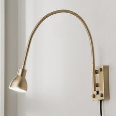 a light that is on the side of a white wall next to a black cord