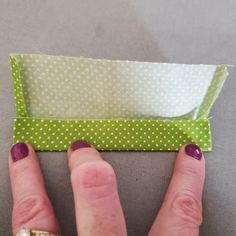 a woman's hand with purple nail polish on her nails next to an origami box