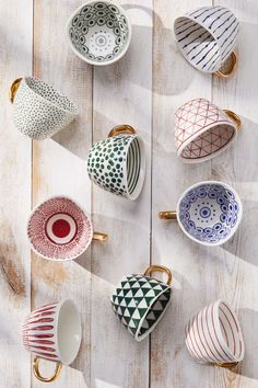 coffee cups lined up on a wooden table with gold handles and designs painted on them