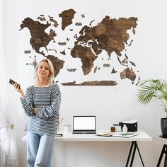 a woman standing in front of a wall with a world map on it's side