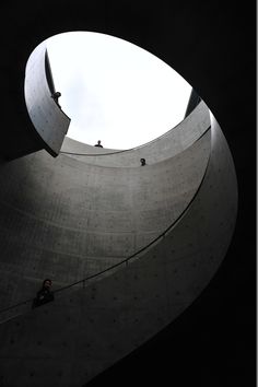 two people are climbing up the side of a building with a sky background and an open round window