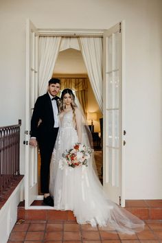 a bride and groom standing in front of an open door