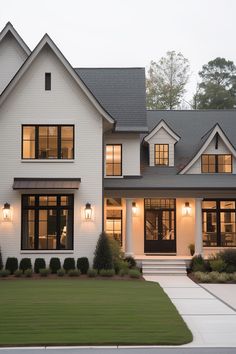 a large white house with lots of windows and lights on it's front porch