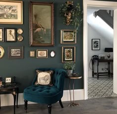 a living room with green walls and pictures on the wall, including a blue chair