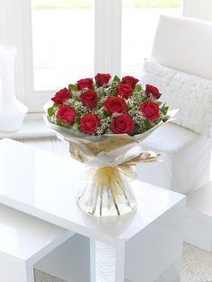 a bouquet of red roses sitting on top of a table next to a white couch