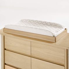 a wooden dresser with a mattress on it's top shelf and drawers in front of it