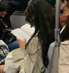 some people sitting on a train and one is reading a book