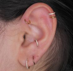 a woman wearing three different types of ear piercings