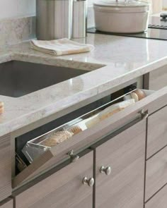 a kitchen sink with an open pull out drawer in front of the sink and countertop