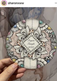 a person holding up a coaster with an intricate design on the front and back side