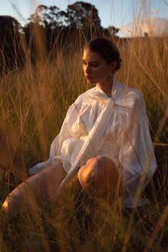 a woman is sitting in the tall grass