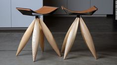 two wooden chairs sitting next to each other on top of a cement floor in front of white cabinets