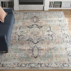 a blue couch sitting in front of a fireplace next to a rug on top of a hard wood floor