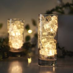 two glass vases filled with ice and lights