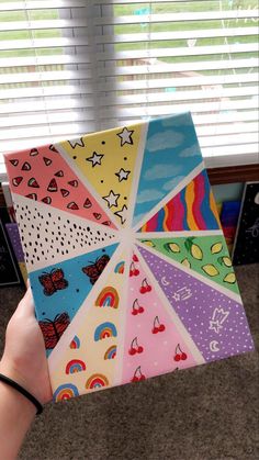 someone is holding up a colorful box with different designs on it and the bottom half has an umbrella painted on it