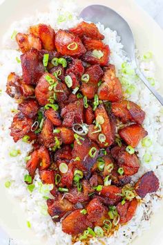 a white plate topped with rice and meat next to a spoon on top of it