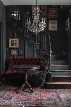 a living room with a red couch, chandelier and rug on the floor