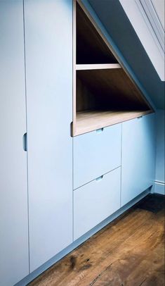 an attic bedroom with blue cupboards and wooden floors