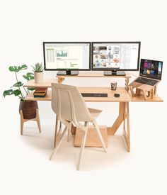 two computer monitors sitting next to each other on top of a wooden desk with chairs