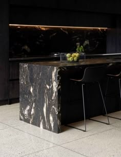 a kitchen with black marble counter tops and bar stools next to it on the floor