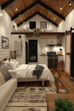 a bed sitting in the middle of a living room next to a kitchen